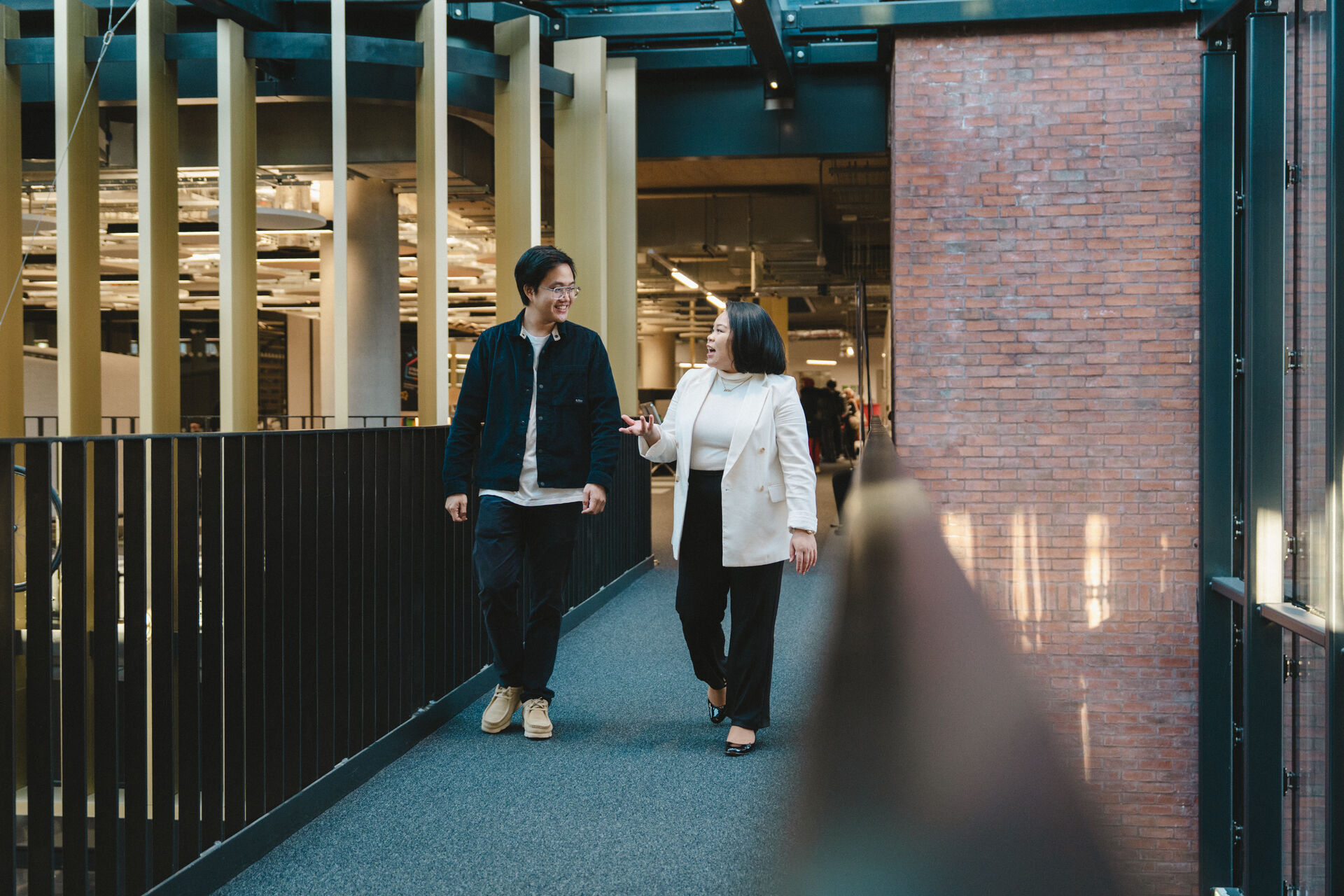Two students who appear to Southeast Asian walk through a modern university building