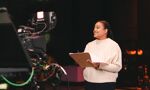 A student is holding a clipboard in a tv studio, with a camera in shot