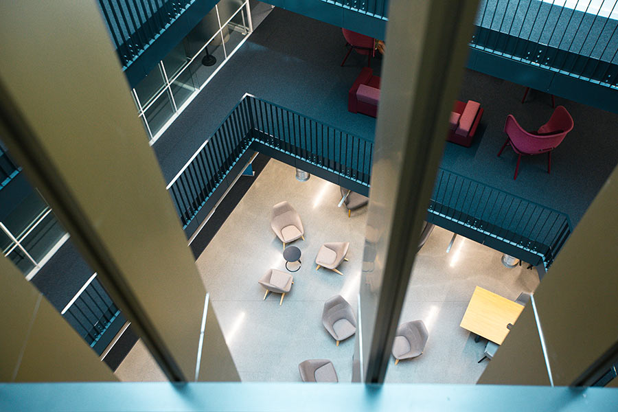 A high-angle view looking down through railings at a modern interior space with various seating arrangements on different levels.
