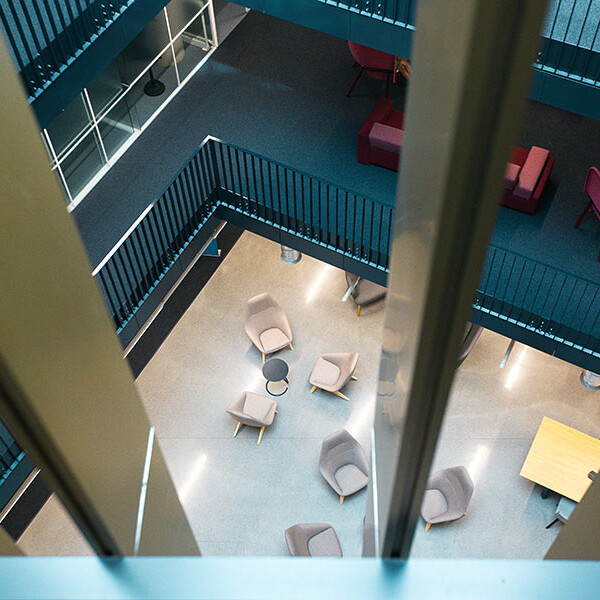 A high-angle view looking down through railings at a modern interior space with various seating arrangements on different levels.