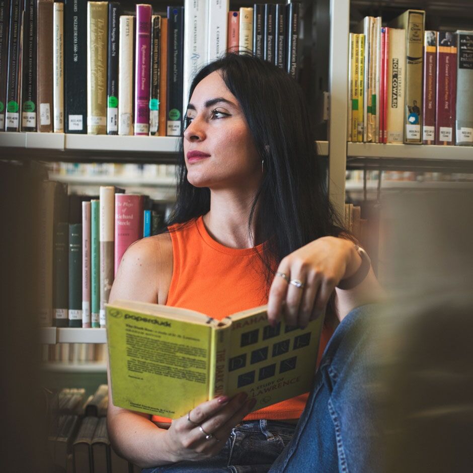 A student reflects while reading in the library