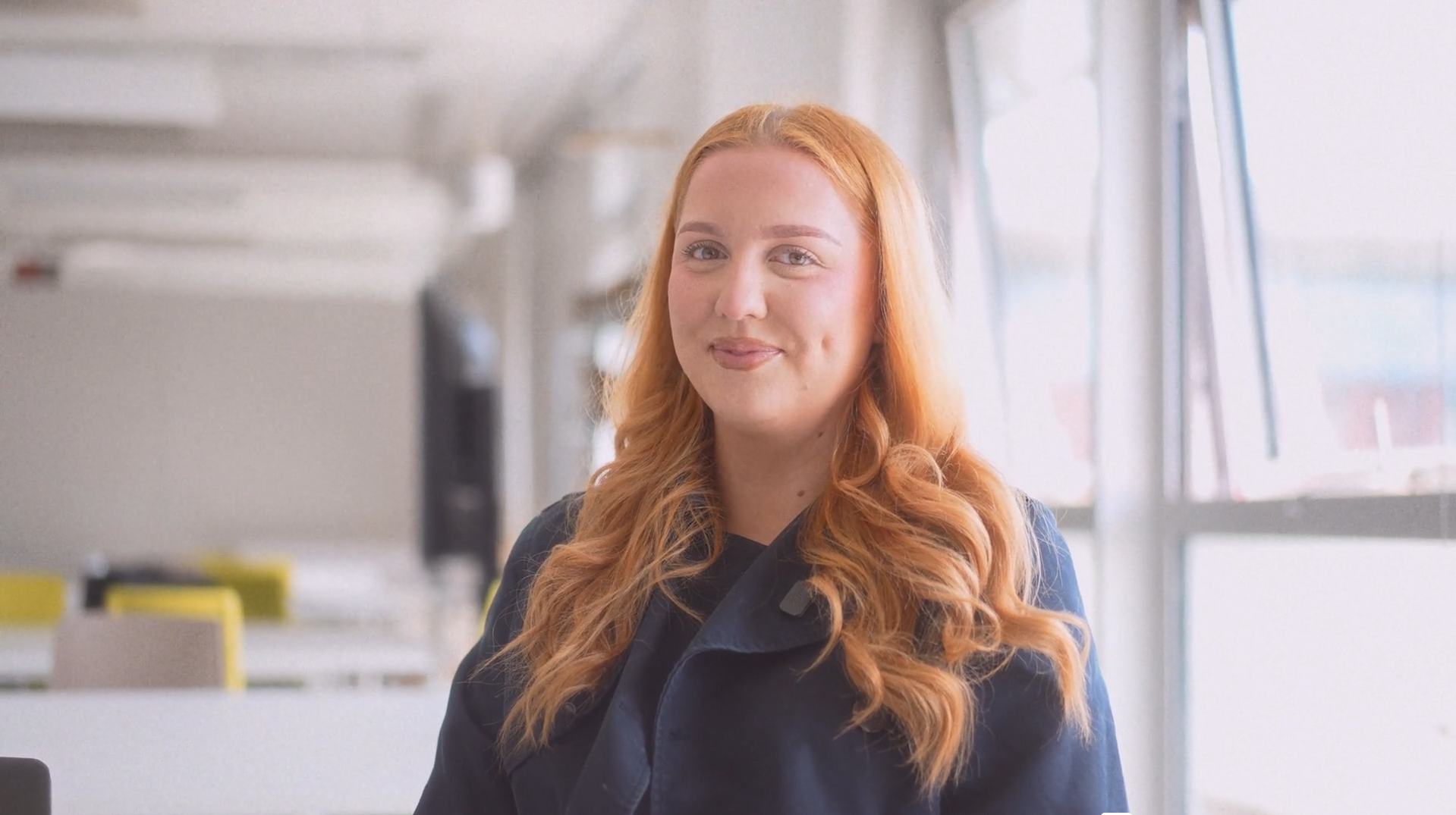 Student with ginger/red hair smiling while looking into camera