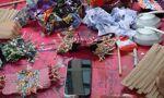 An overhead view of a work surface covered in pink paint splatters with various fabric scraps and materials for a crafting workshop