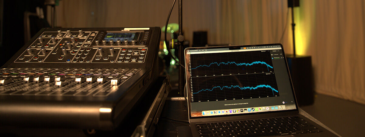 A sound engineering setup with a mixing console and a laptop displaying audio waveforms.