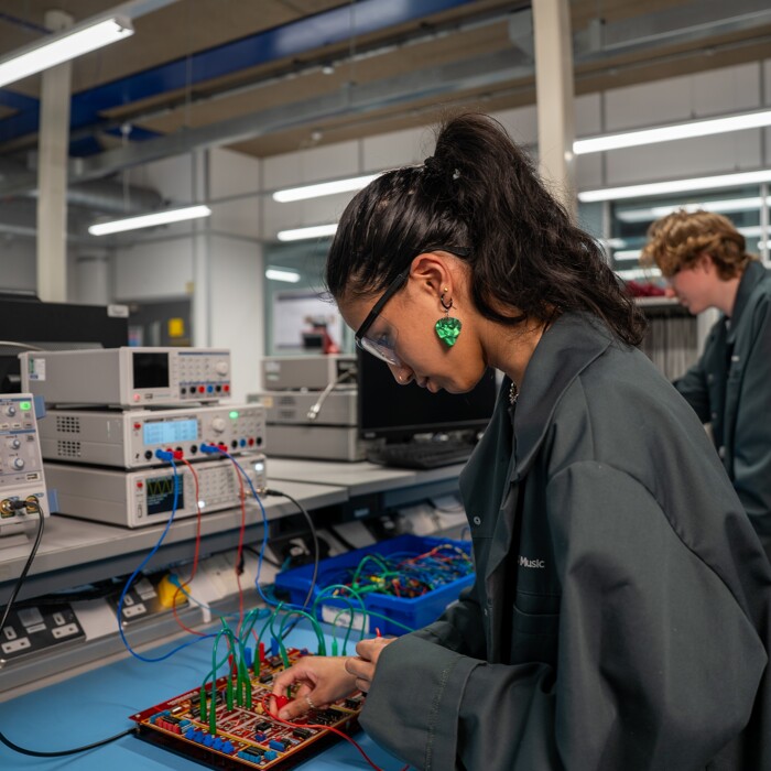 Student using sound engineering audio software/hardware wearing safety gear and goggles