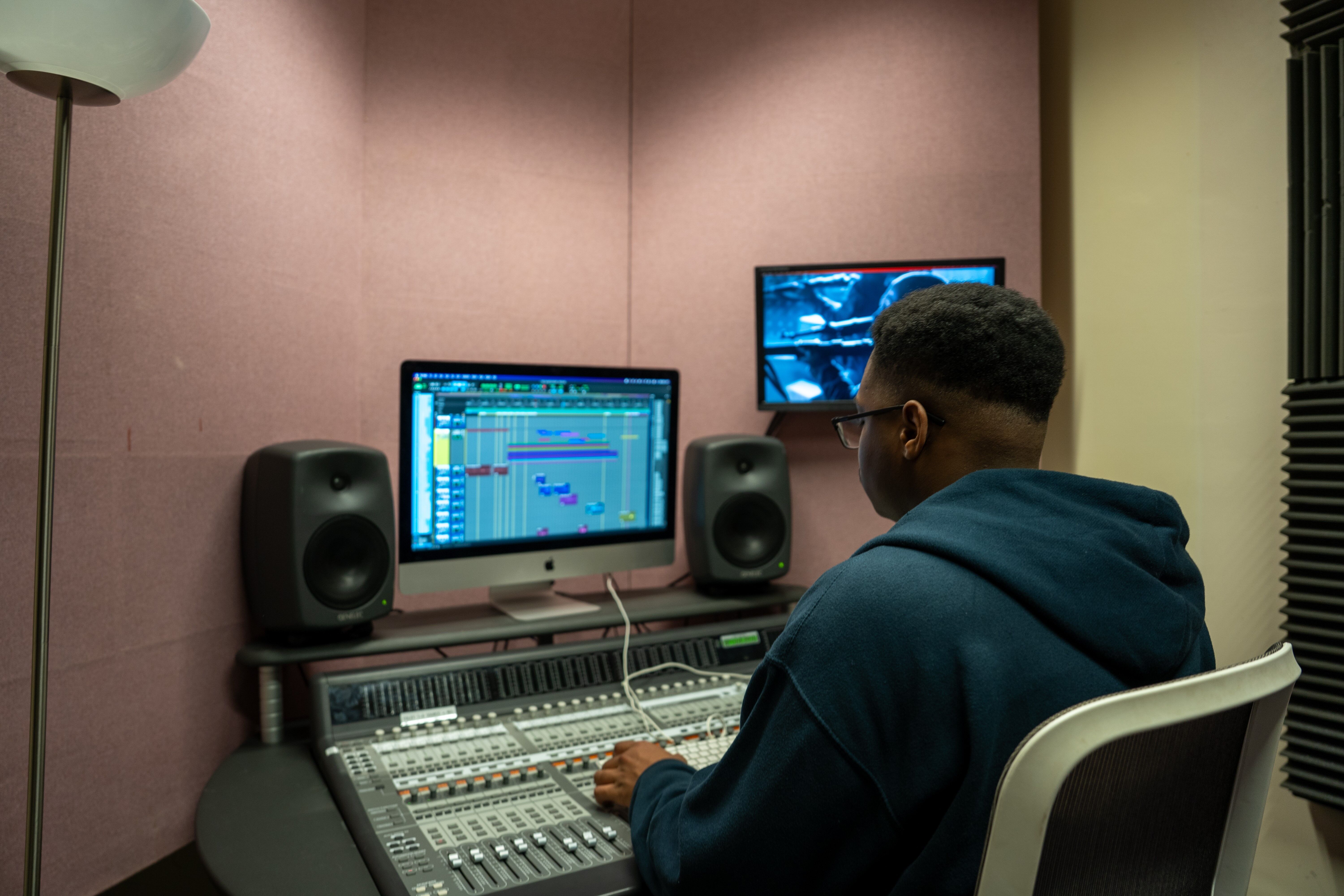 Student sat using computer in sound engineering studio