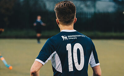 Student footballer looking away from the camera across the football pitch