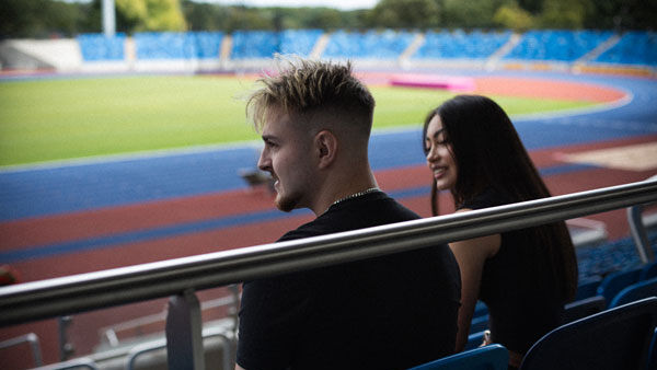 Two students talk whilst sitting in the stands of the Alexander Stadium