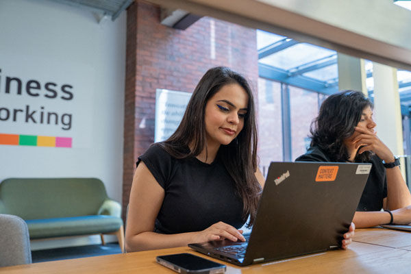 Two STEAMhouse members work on laptops in the STEAMhouse co-working space