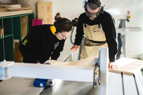 Two makers using woodcutting equipment in the STEAMhouse's Maker studio