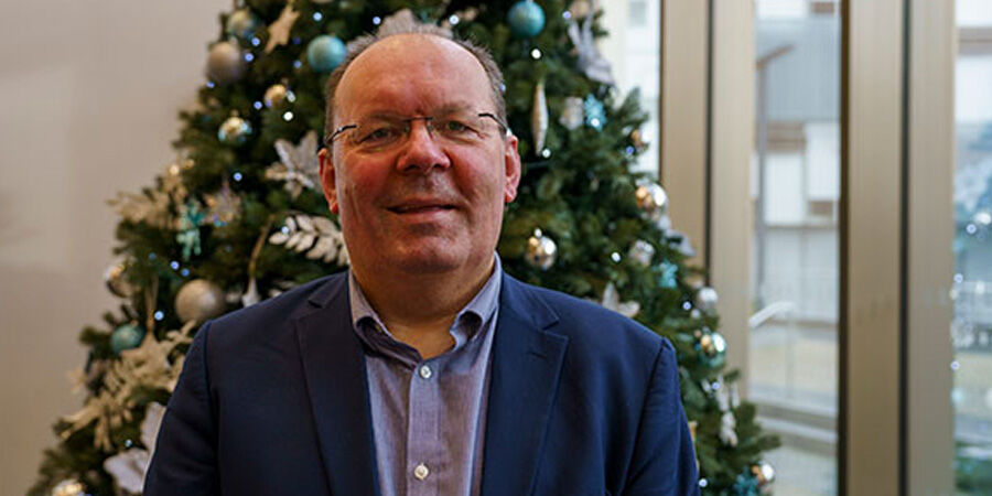Stephen Maddock standing in front of a Christmas tree.