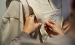 Student sewing white coat