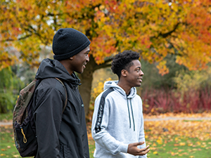 Two students in Cannon Hill park with colourful autumn leaves in the background