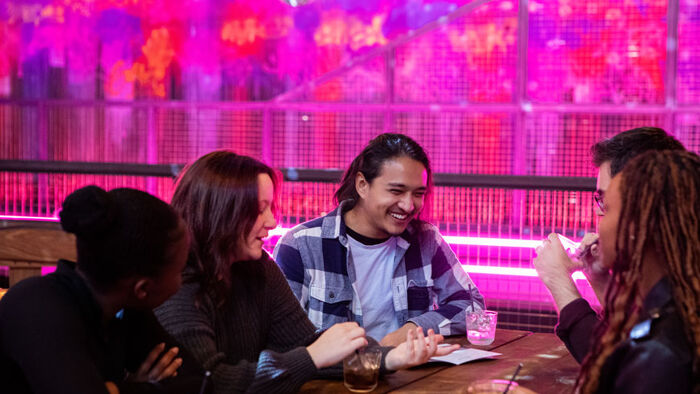A group of students laugh. They are sitting around a table drinking in Lane 7.