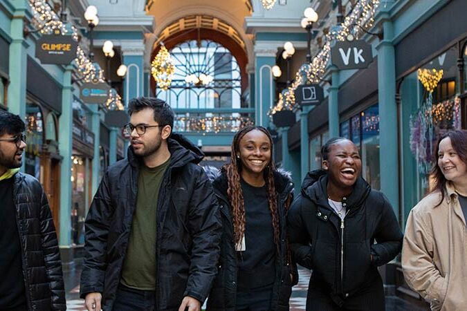 A group of students walk through Great Western Arcade smiling and talking