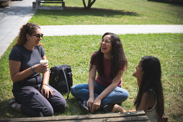 Three students sit and talk in Eastside Park