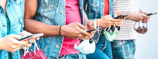 People using their phones and holding face masks