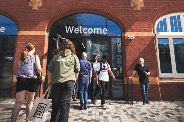 Students walking into the STEAMhouse building at BCU with a welcome sign above the door
