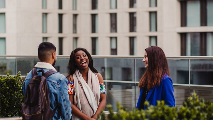 three students talk and laugh outside